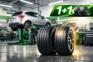 Deux pneus neufs en atelier auto avec voiture sur pont et mécanicien, visuel promo 1 acheté = 1 offert.