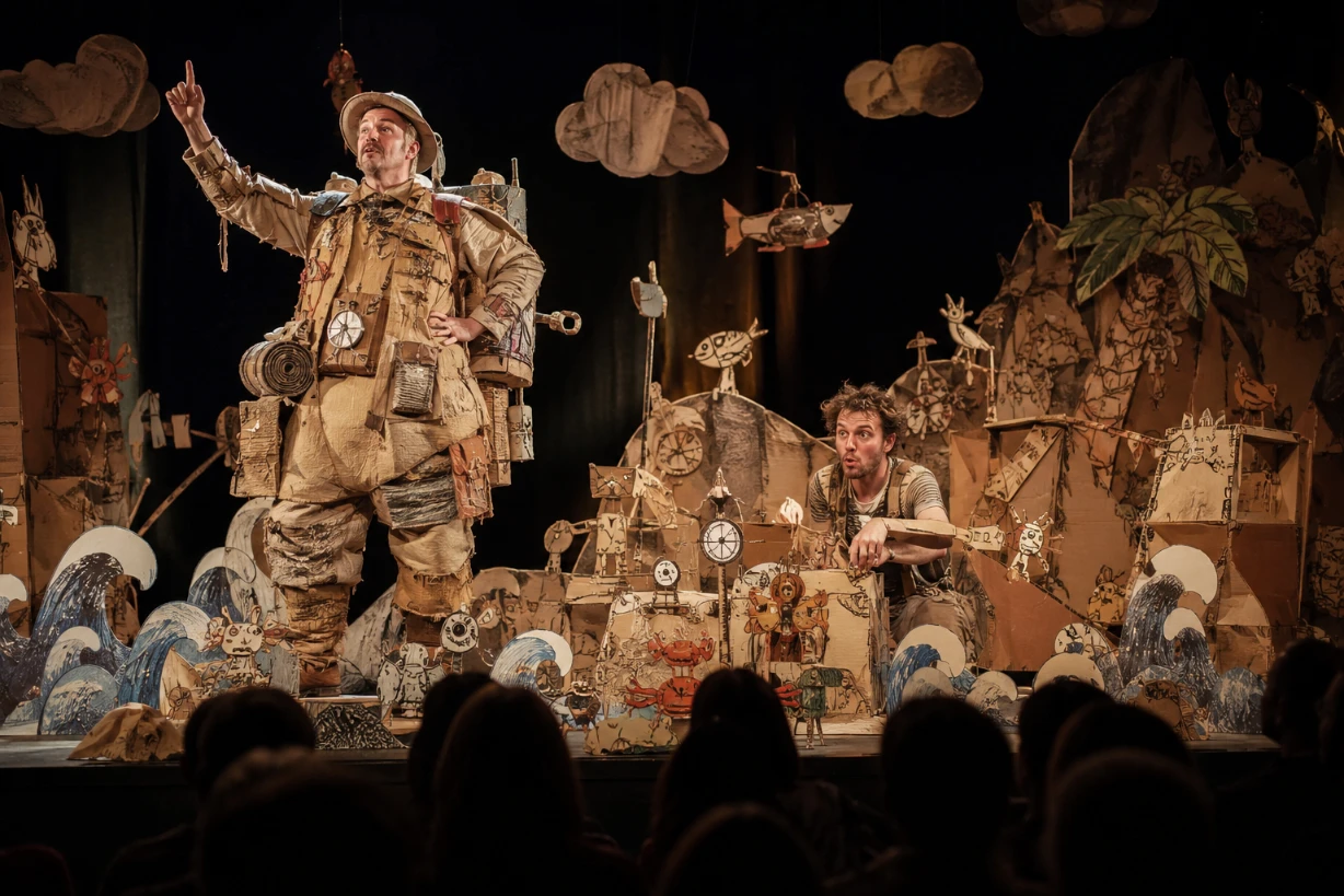 Deux comédiens sur scène dans un décor en carton absurde et poétique de théâtre comique.