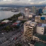 Vue aérienne d’une ville côtière des Philippines après un séisme, avec secours et dégâts visibles.