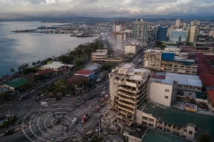 Vue aérienne d’une ville côtière des Philippines après un séisme, avec secours et dégâts visibles.